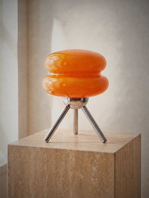 Carrara Mini, stacked orange glass rings on a polished chrome tripod, unlit