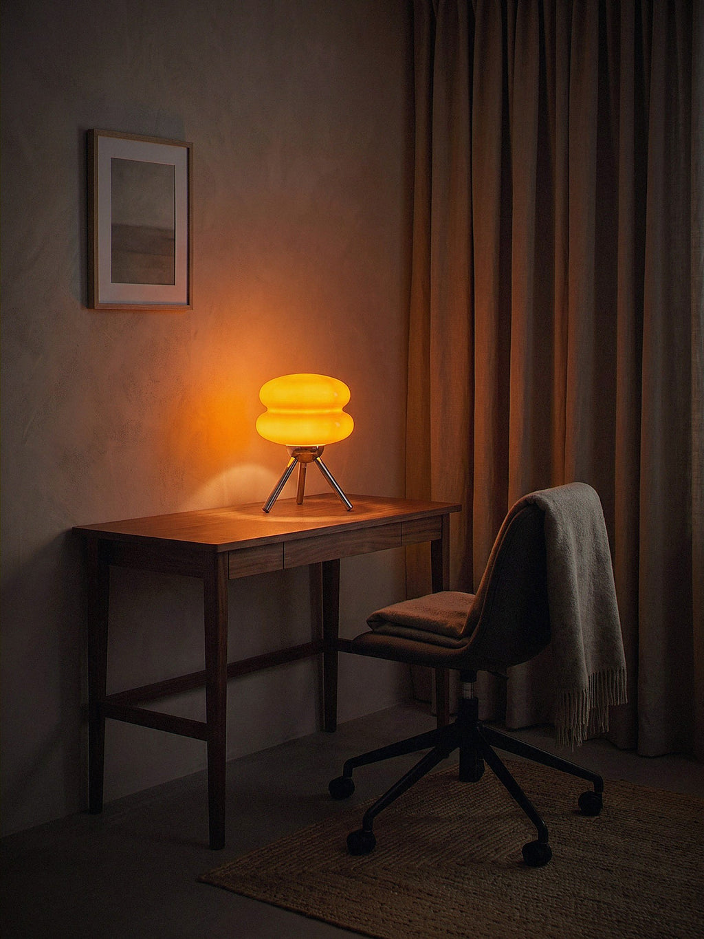 Carrara Mini, stacked orange glass rings on a polished chrome tripod lit as the only light source in a compact work nook