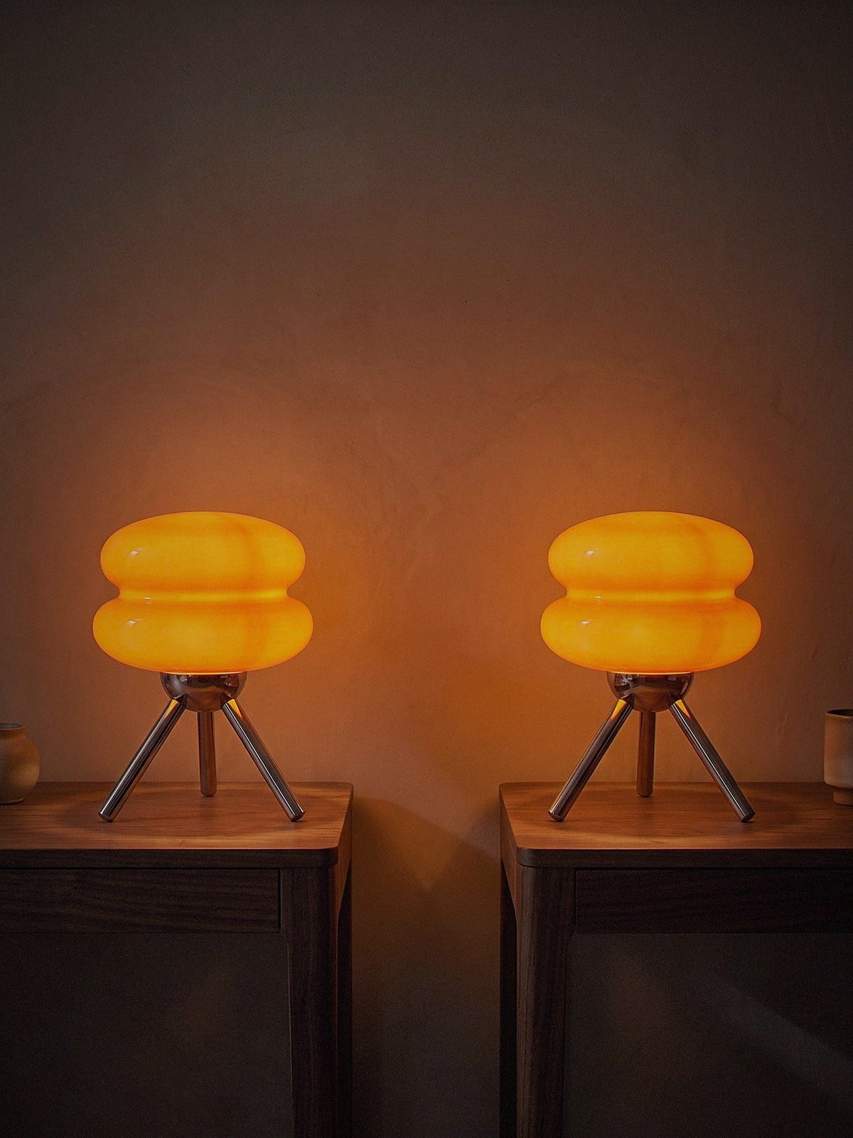 Two Carrara Mini lamps lit on bedside tables, sold individually
