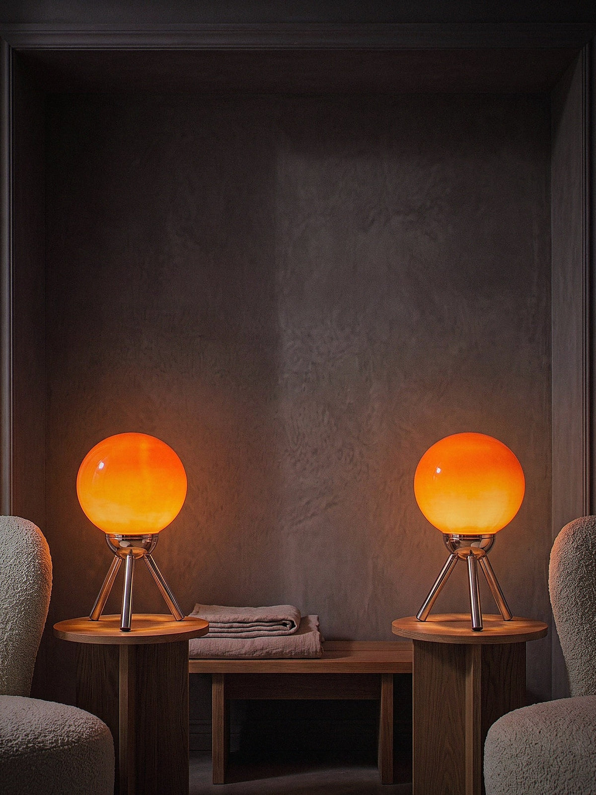 Two Fjord lamps lit on side tables in a dim reading alcove, sold individually