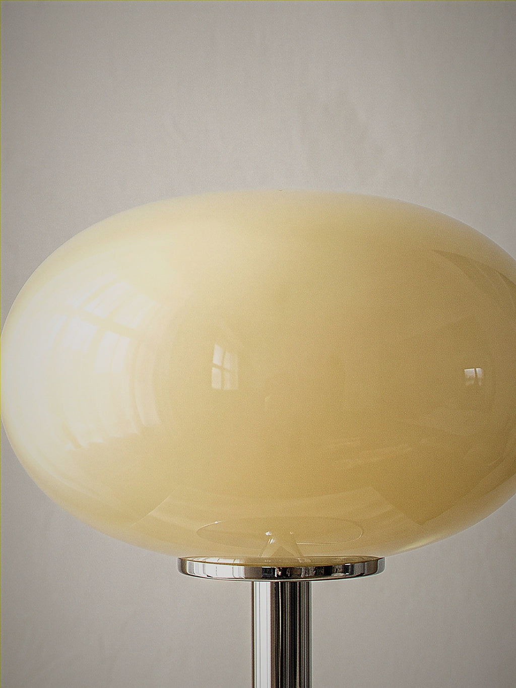 Close detail of Halo, a soft cream frosted glass dome on a slim polished chrome base