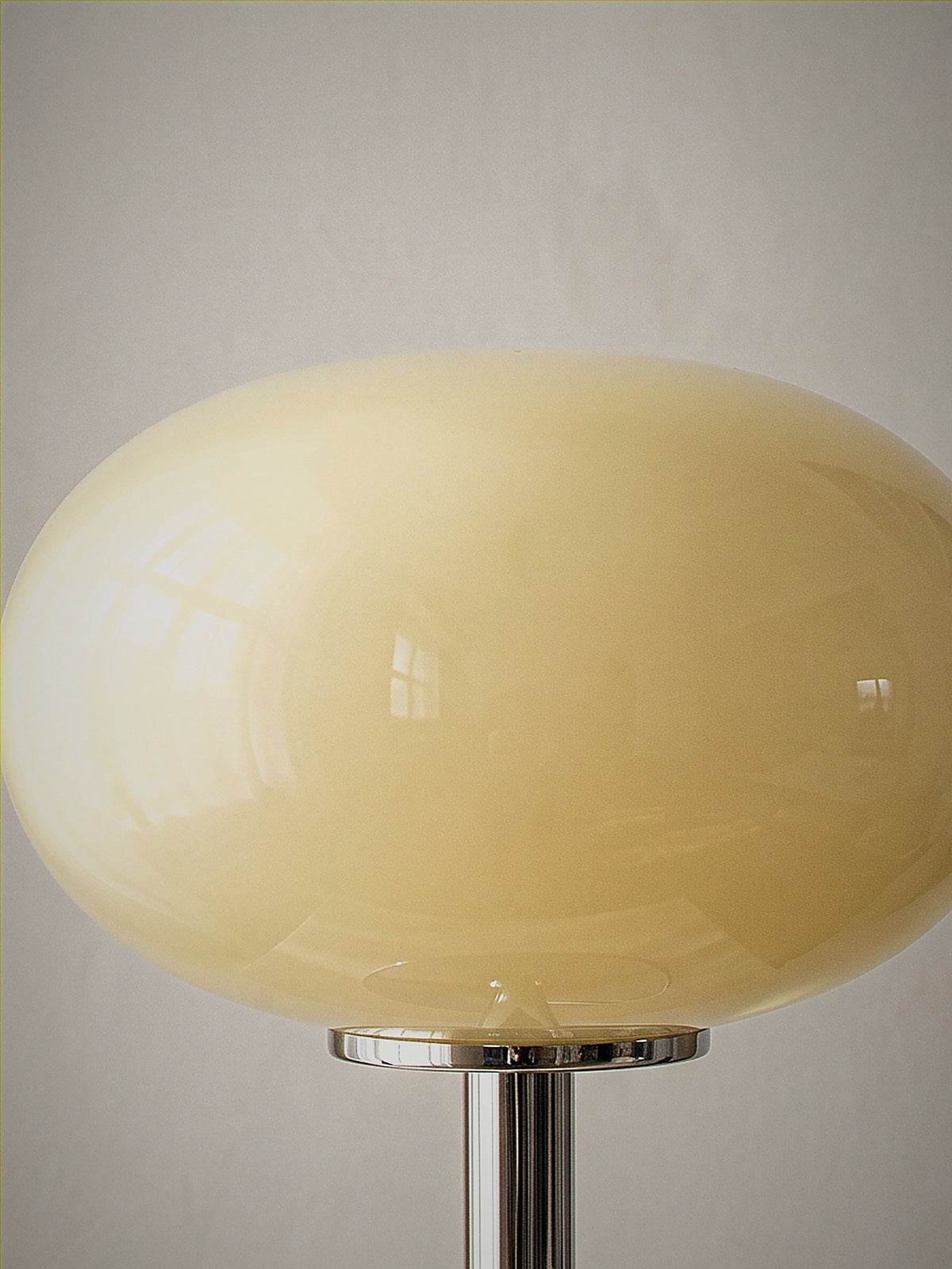 Close detail of Halo, a soft cream frosted glass dome on a slim polished chrome base