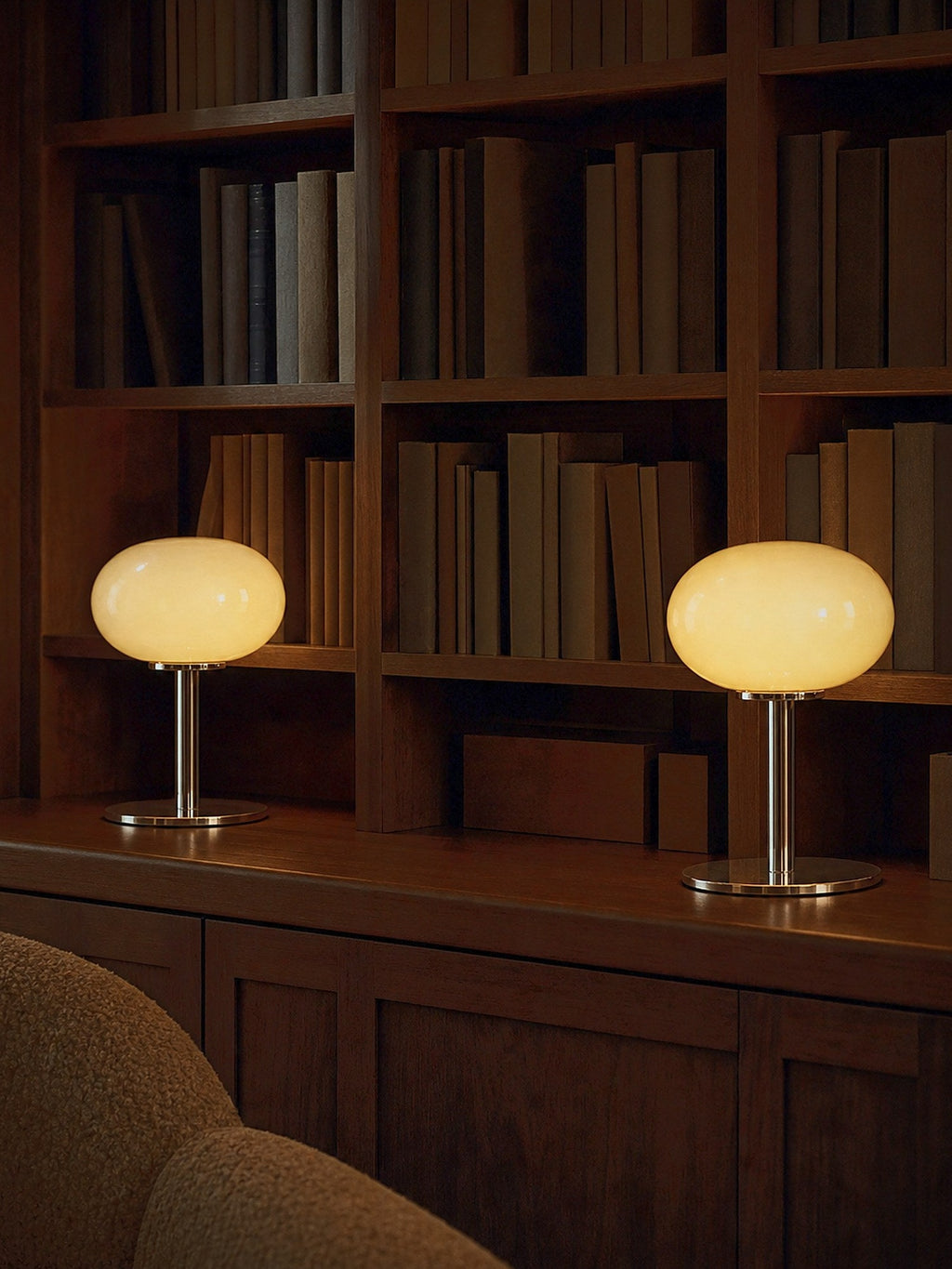 Two Halo lamps lit on a console in front of walnut bookshelves, sold individually