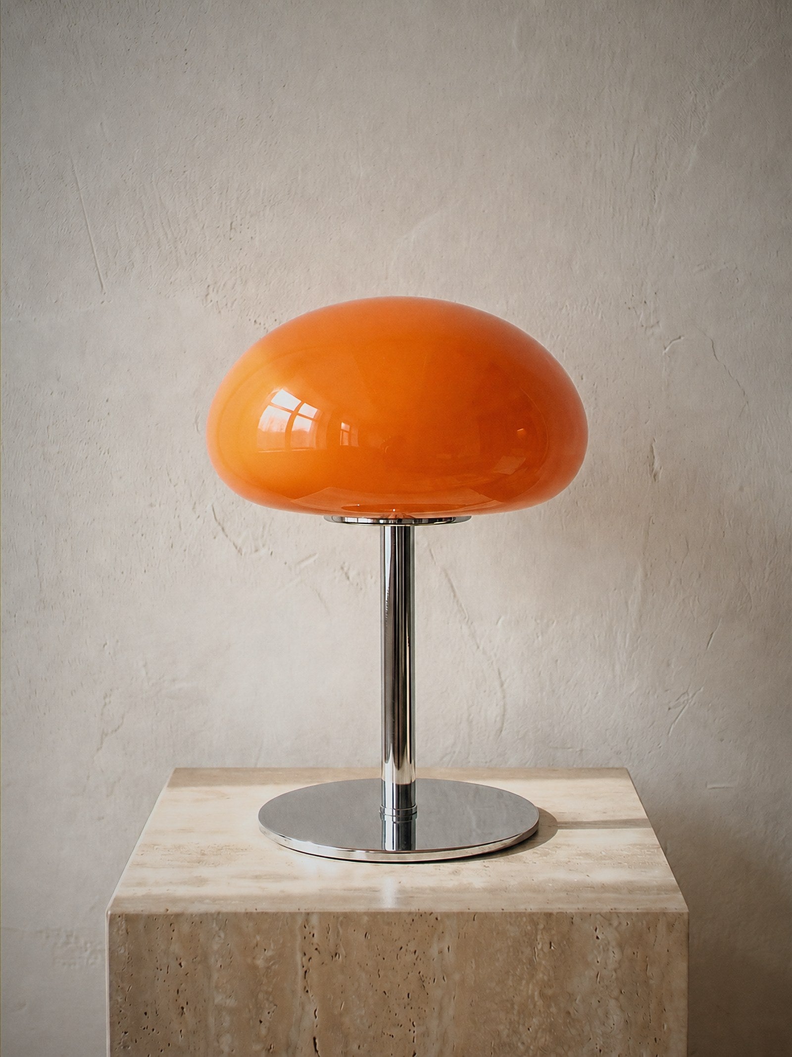 Nimbus, an orange glass dome shade on a slim chrome stem and round chrome base, unlit