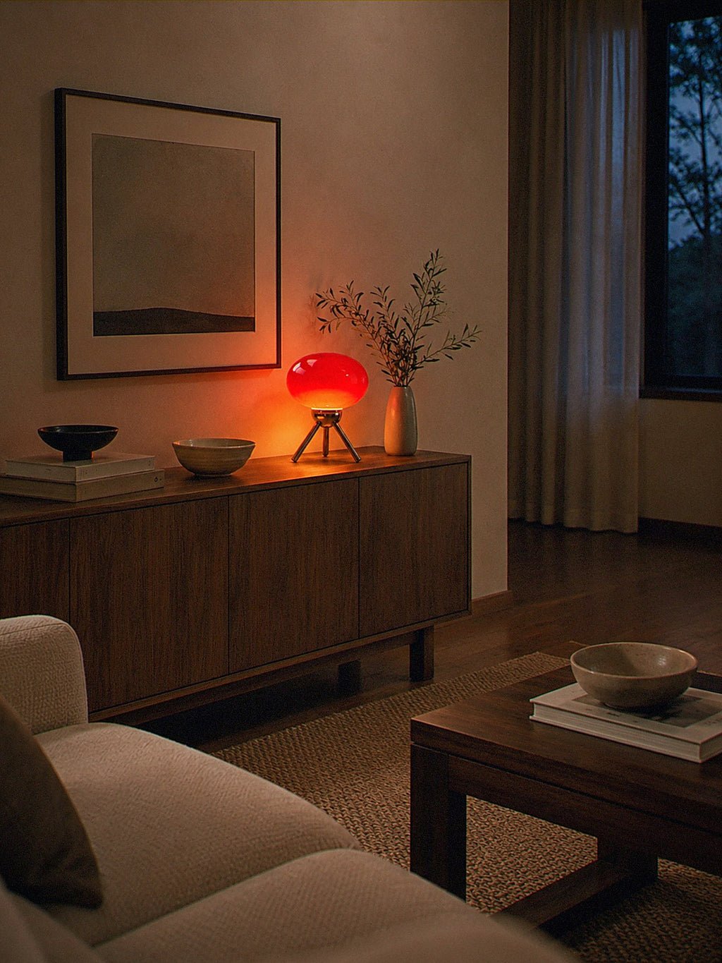 Prism, a red glass dome lamp on a polished chrome tripod lit as the only light source in a dark living room