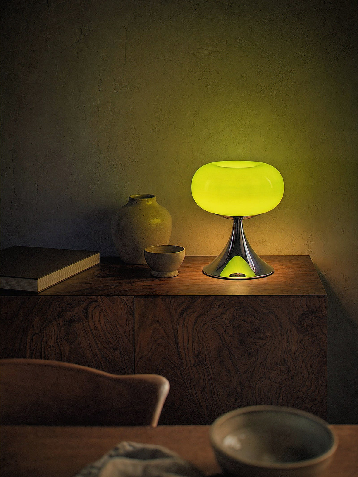 Rondo, a green glass dome on a polished chrome trumpet base, switched on in an intimate dining nook at night