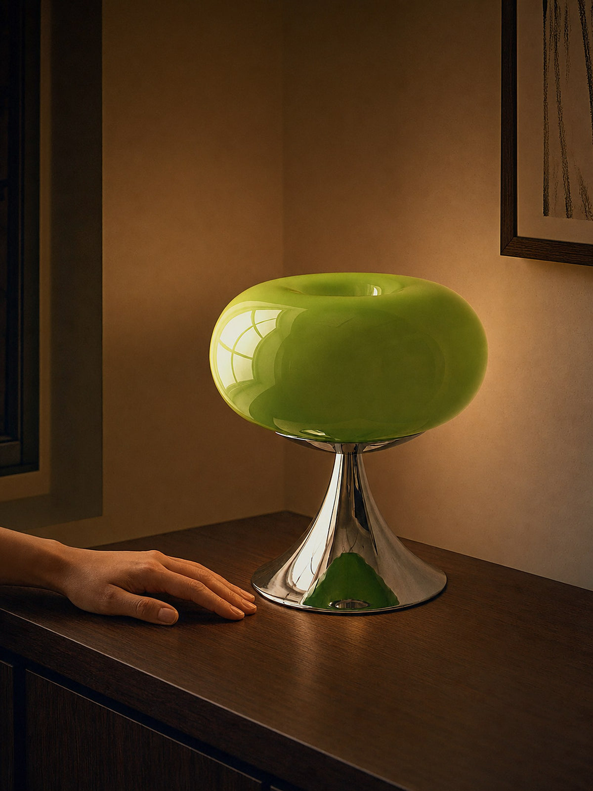 A hand resting beside Rondo, a green glass dome on a polished chrome trumpet base, showing its true size