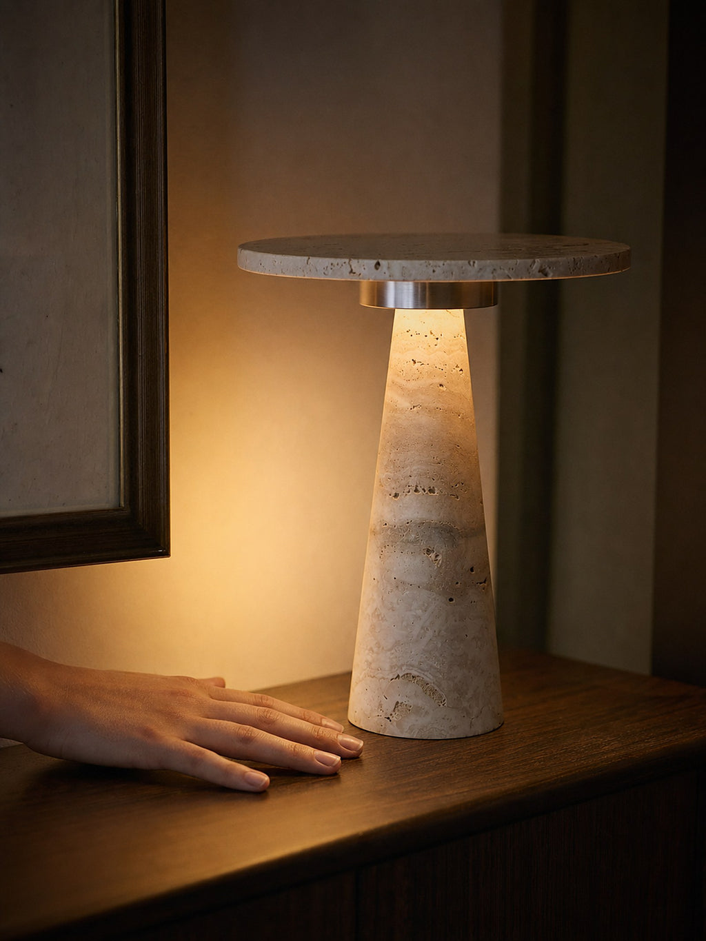 A hand resting beside Terrazzo, a travertine cone topped with a travertine disc, showing its true size