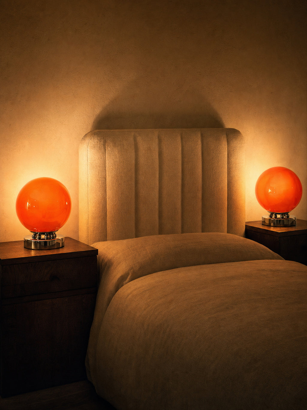 Two Whisper lamps lit on bedside tables either side of an upholstered bed, sold individually