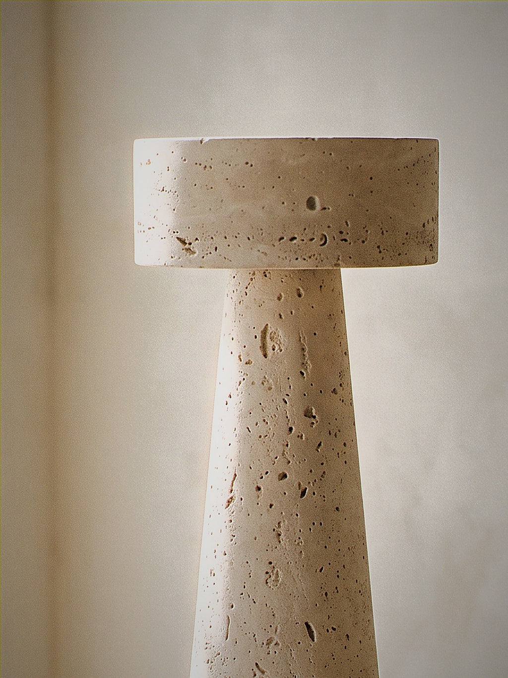 Close detail of Zen, a tapered travertine column topped with a stone disc